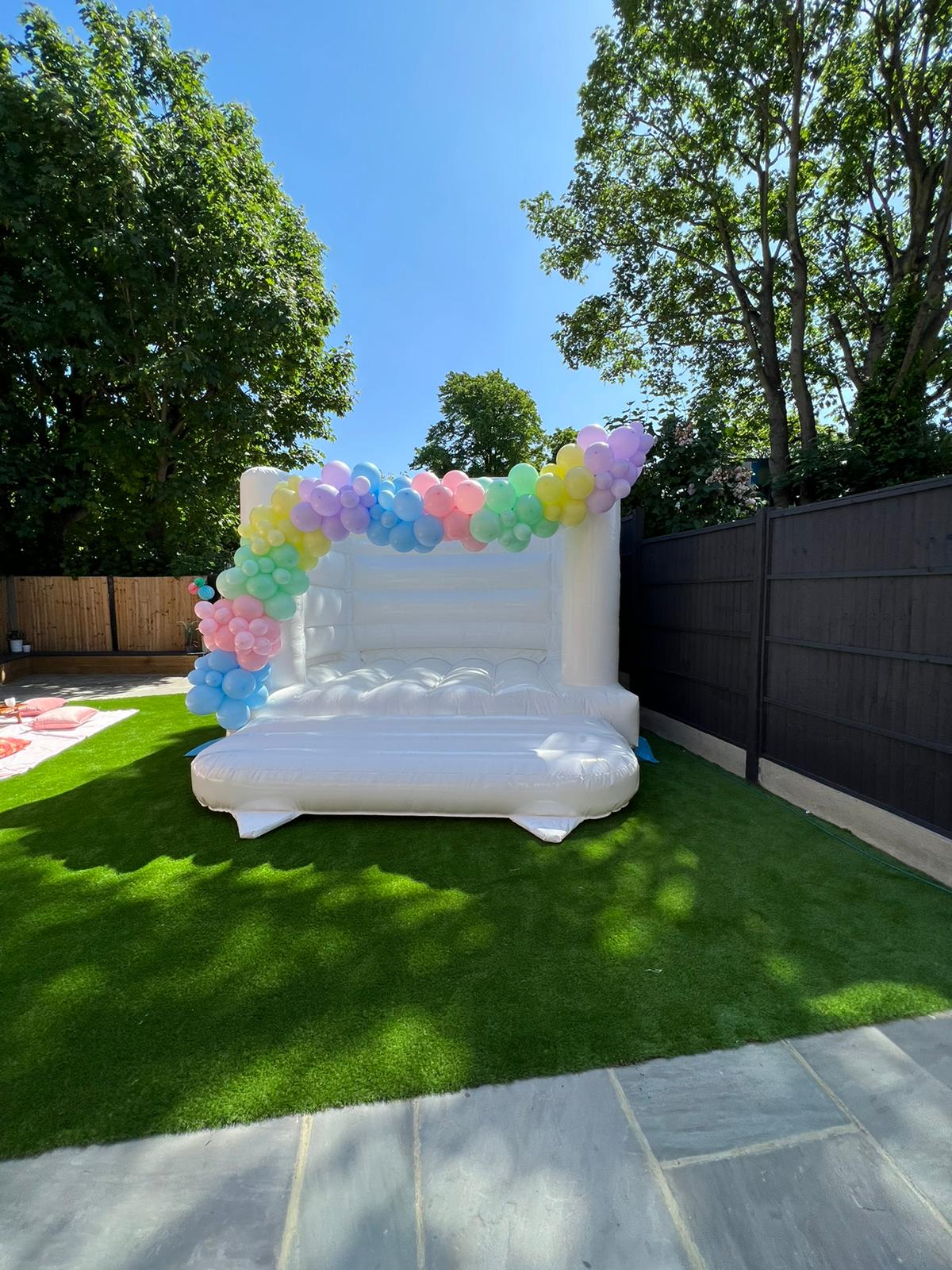 white bouncy castle with balloon garland